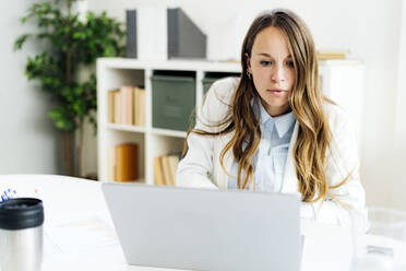 Businesswoman using laptop at desk in office - GIOF14960