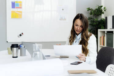 Businesswoman analyzing document at desk in office - GIOF14967