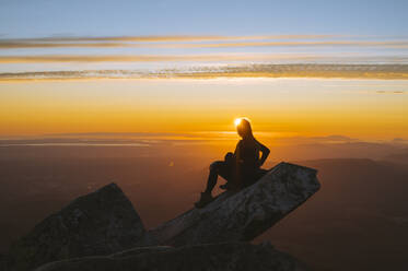Silhouette of a woman on a mountain peak at sunset - CAVF95990