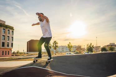 Adult man surfing in circuit with a skate surf at sunset - CAVF96015