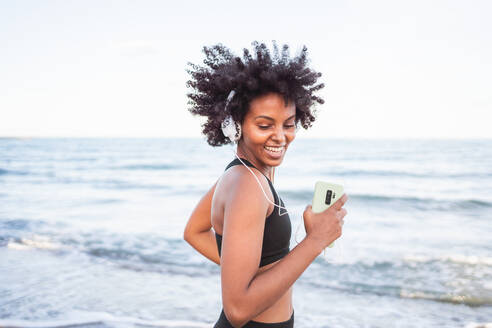 Schwarze Frau, die lacht und Spaß beim Tanzen am Strand hat - CAVF96035