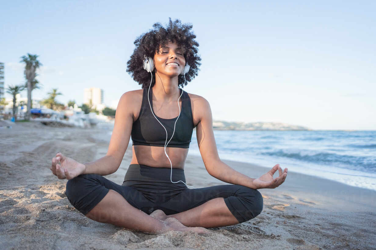 Young fit Black woman in seated balancing yoga pose exercising on beach  Stock Photo - Alamy