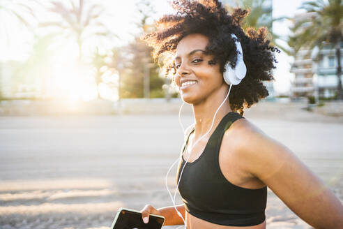 Black woman with afro hair running happily on the beach - CAVF96048