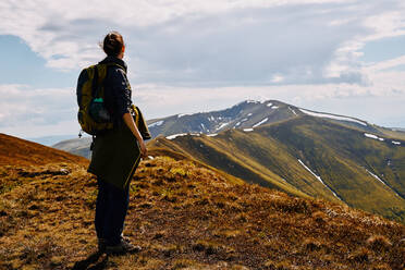 Woman mountain traveler looks at the mountain range. - CAVF96093