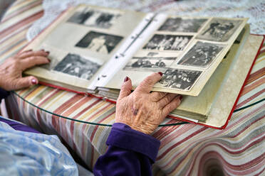 Unrecognizable senior woman watching an album of old photographs - CAVF96132
