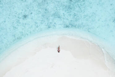 Aerial Top Down View Of Female Model Lying On White Sand Beach In South Male Atoll, Maldives. - AAEF14270