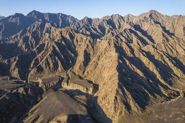 Luftaufnahme eines Canyons zwischen felsigen und trockenen Bergen in der Wüste im Bundesstaat Ajman, Vereinigte Arabische Emirate. - AAEF14296