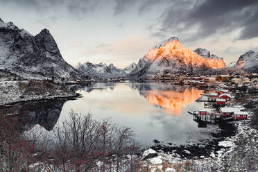 Clouds at dawn over traditional Rorbu and Olstind mountain reflected in sea, Reine Bay, Nordland, Lofoten Islands, Norway, Scandinavia, Europe - RHPLF21758