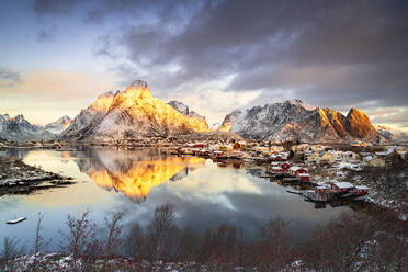 Dramatischer Himmel in der Morgendämmerung über dem schneebedeckten Berg Olstind, Reine Bay, Nordland, Lofoten, Norwegen, Skandinavien, Europa - RHPLF21759