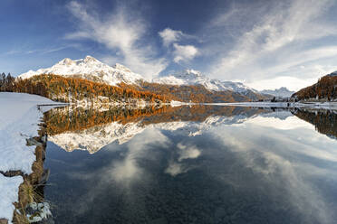 Herbstwälder und schneebedeckte Berge spiegeln sich im klaren Wasser des Champfer Sees bei Sonnenuntergang, Engadin, Graubünden, Schweiz, Europa - RHPLF21808