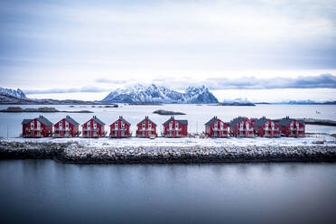 Luftaufnahme von roten Rorbu-Hütten in einer Reihe inmitten des kalten Meeres im Winter, Svolvaer, Landkreis Nordland, Lofoten, Norwegen, Skandinavien, Europa - RHPLF21876