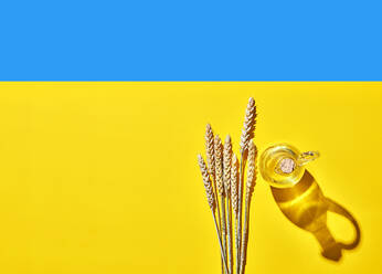 Ähren von Weizen von Öl-Flasche auf blau und gelb ukrainischen Flagge - KSWF02244