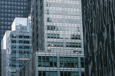 From below of contemporary high rise buildings with glass mirrored walls located on street of modern city - ADSF34247