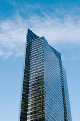 Blick von unten auf ein modernes Hochhaus mit verspiegelten Glaswänden in einer Straße einer modernen Stadt - ADSF34255