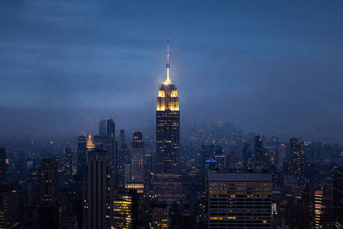 Modern high rise buildings with glowing lights located in downtown of New York City on night time against cloudless sky - ADSF34260