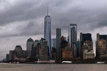 Zeitgenössische Hochhäuser am Ufer in der Nähe von plätschernden Meer gegen bewölkten Himmel in bewölktem Wetter in New York City gelegen - ADSF34262