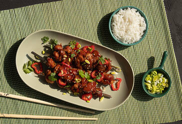 Top view of delicious marinated chicken on skewers topped with greens served on table with rice and leek in restaurant - ADSF34319