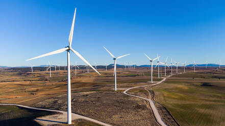 Modern windmills located in dried filed in countryside on sunny day under blue sky in Cantabria, Spain - ADSF34384