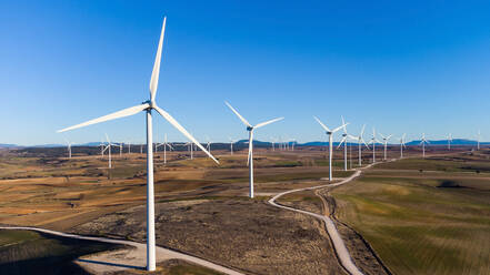 Moderne Windmühlen in getrockneten Feldern auf dem Lande an einem sonnigen Tag unter blauem Himmel in Kantabrien, Spanien - ADSF34384