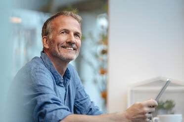 Smiling businessman with tablet PC sitting in cafe - GUSF07219