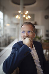 Thoughtful businessman wearing eyeglasses sitting in cafe - GUSF07260
