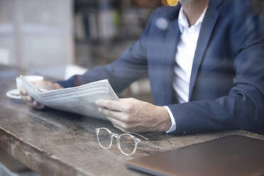 Geschäftsmann mit Zeitung am Tisch im Café sitzend - GUSF07277