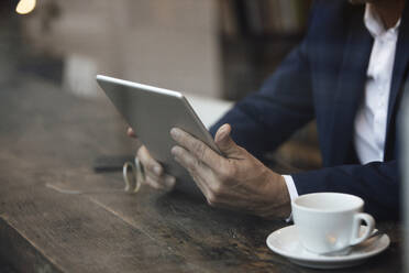 Geschäftsmann mit Kaffeetasse und Tablet-PC am Tisch im Café sitzend - GUSF07281