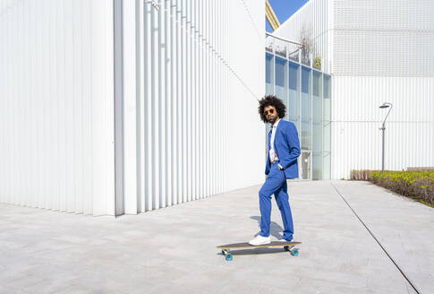 Geschäftsmann mit Skateboard stehend Hand in der Tasche an einem sonnigen Tag - OIPF01408