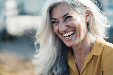 Businesswoman with gray hair laughing on sunny day - JOSEF08293