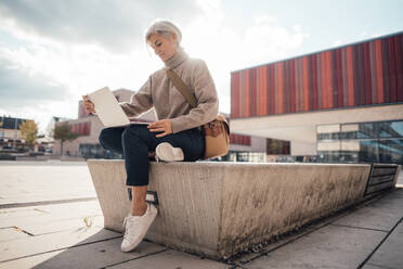 Geschäftsfrau mit Laptop auf einem Sitz auf dem Gehweg - JOSEF08297