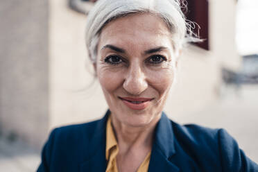 Lächelnde Geschäftsfrau mit grauem Haar vor einem Bürogebäude - JOSEF08349