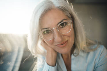 Smiling businesswoman with gray hair wearing eyeglasses in office - JOSEF08448