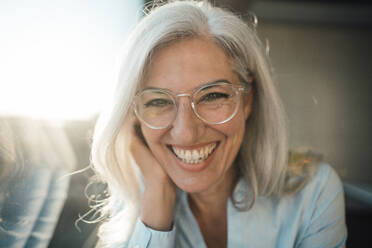 Cheerful businesswoman with gray hair wearing eyeglasses in office - JOSEF08449