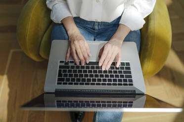 Hände einer Frau mit Laptop auf einem Sessel sitzend - OGF01118