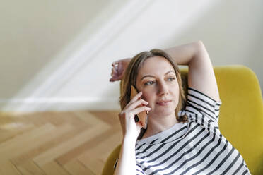 Woman talking on mobile phone sitting on chair - OGF01128