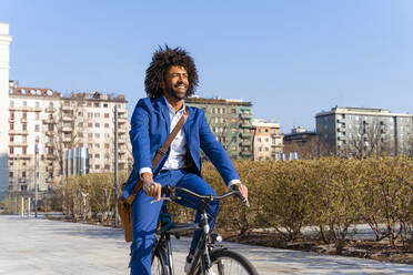 Glücklicher Geschäftsmann mit Umhängetasche auf dem Fahrrad sitzend - OIPF01458