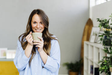 Lächelnde schöne Frau mit Kaffeetasse zu Hause - GIOF15005