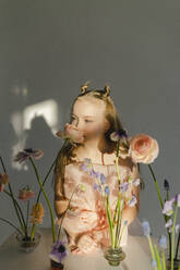 Mädchen, das an einer frischen Blume riecht, steht am Tisch - SEAF00715