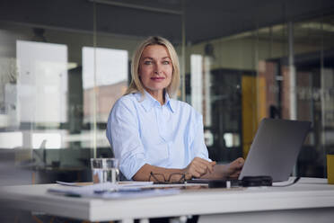 Businesswoman with laptop at desk in office - RBF08801