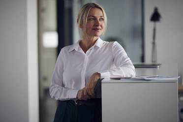 Lächelnde Geschäftsfrau mit Tablet-PC vor einem Schrank im Büro - RBF08817