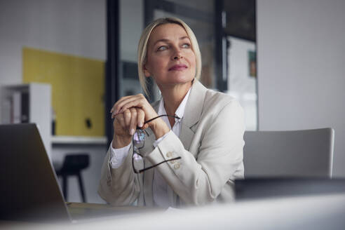 Geschäftsfrau mit Brille und Laptop am Schreibtisch im Büro - RBF08825