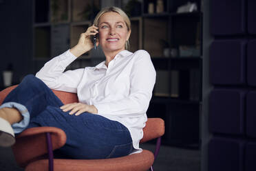 Smiling businesswoman talking on mobile phone in office - RBF08844