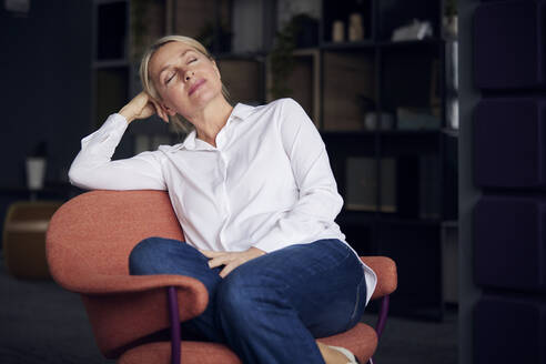 Geschäftsfrau mit geschlossenen Augen entspannt auf einem Stuhl im Büro - RBF08849