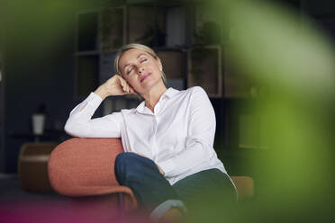 Businesswoman with eyes closed relaxing on chair - RBF08850