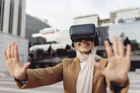 Glückliche Geschäftsfrau im Virtual-Reality-Simulator gestikuliert auf einem Stoppschild - JCCMF05934