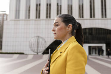 Businesswoman with tablet PC standing in front of building - JCCMF05938