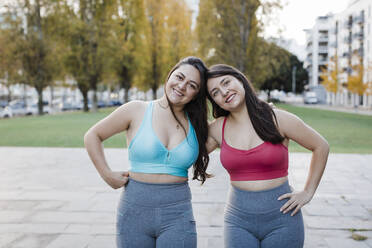 Smiling women in sports bra standing at public park - DCRF01083