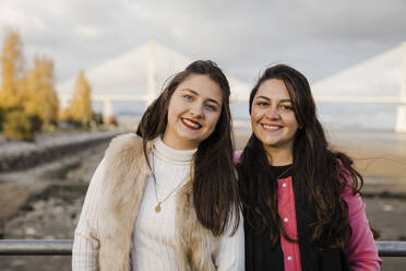 Glückliche Frauen stehen am Geländer vor einer Brücke - DCRF01096