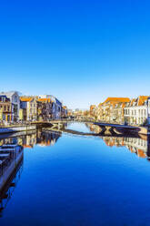 Niederlande, Südholland, Leiden, Klarer blauer Himmel über Stadtkanal mit Brücke in der Mitte - THAF03074