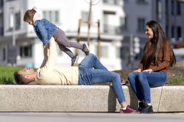 Lächelnde junge Frau schaut auf Vater und Sohn, die den sonnigen Tag zusammen genießen - OCMF02359